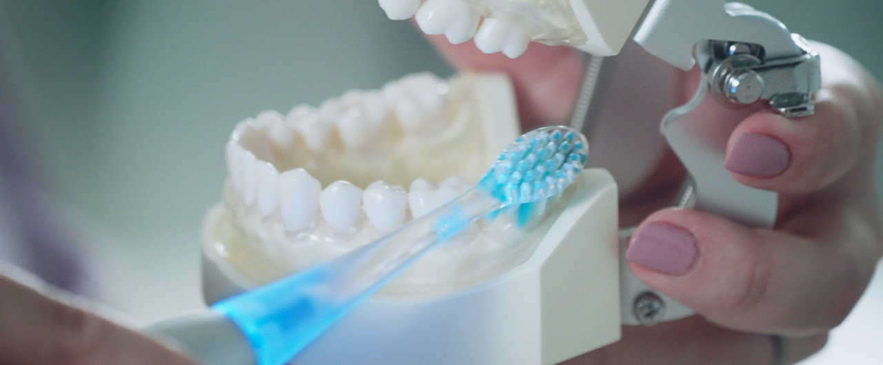 写真：歯列模型にドルツプレミアムW音波振動ハブラシをあてている様子
