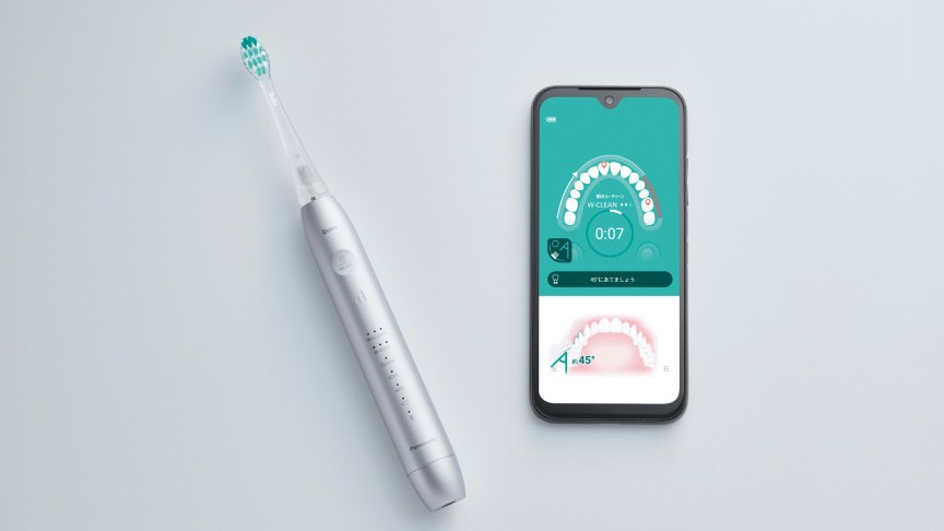 電動歯ブラシと、歯磨きアプリが表示されたスマートフォンが並んでいる。