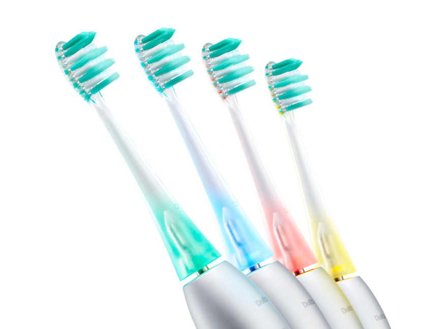 銀色のハンドルと緑・白の毛を持つ電動歯ブラシが4本並んでおり、それぞれネック部分の色が異なる（緑・青・ピンク・黄）。