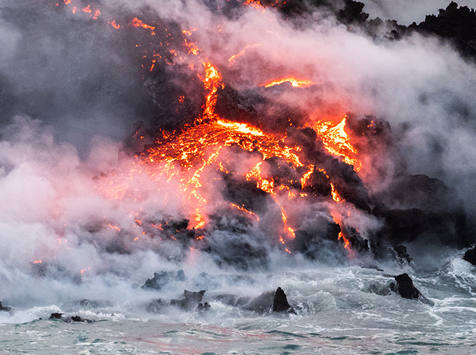 画像：噴煙を上げながら海へ流れ出す溶岩